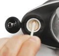 Un bastoncillo de algodón limpia la cámara del Peak, la Joystick Cap está abierta y sujeta por la correa